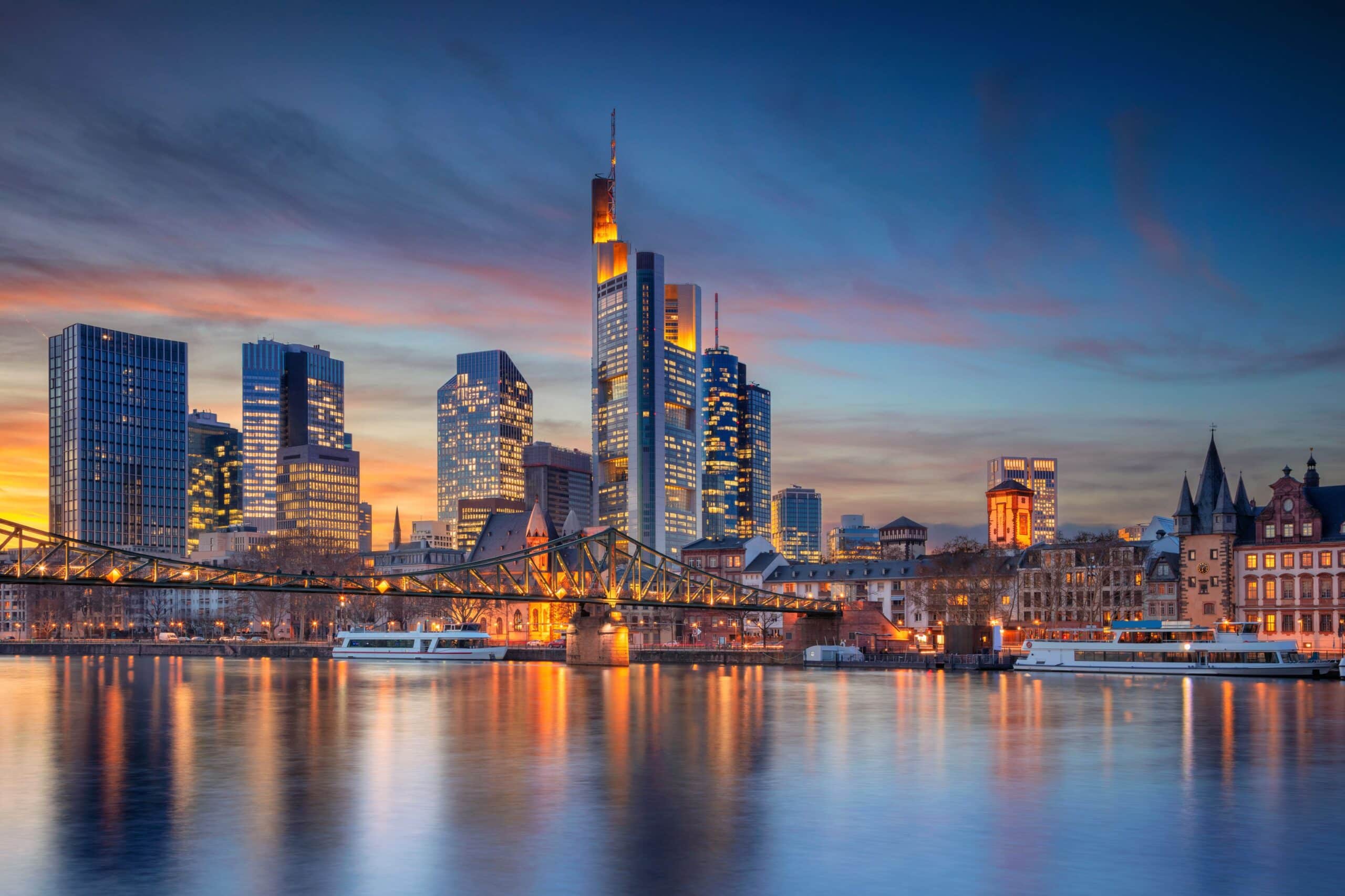 Skyline von Frankfurt bei Sonnenuntergang, mit Spiegelung der Lichter im Main